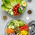 A colorful salad bowl with leafy greens, tomatoes, cucumbers, and feta cheese.
